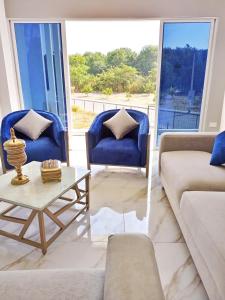 Sala de estar con 2 sillas azules y mesa de centro en Edificio Nuevo Consulado Americano 4Apt Coliving Ecuador, en Guayaquil