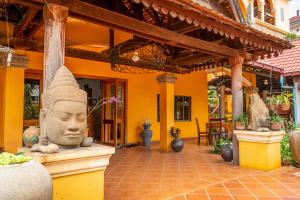 un edificio con una estatua de una cabeza en un patio en DEN HOTEL TOTONOU SIEM REAP, en Siem Reap