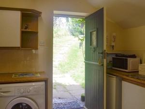 een keuken met een wasmachine en een deur naar een tuin bij The Hayloft in Cinderford