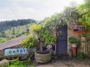 a small house with a blue door and a tree at The Hayloft in Cinderford