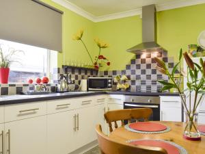 a kitchen with green walls and a wooden table at Lenas Lodge in Birtsmorton