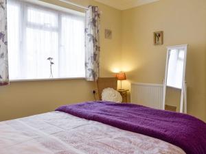 a bedroom with a bed with a purple blanket on it at Lenas Lodge in Birtsmorton