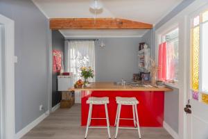 uma cozinha com um balcão vermelho e dois bancos em Braemar House em Oamaru