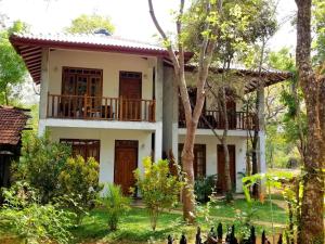 uma casa com uma varanda num jardim em Isanka Lion Lodge em Sigiriya