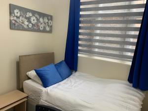 a bedroom with a bed and a window with blue curtains at Luxury Hot Tub - Entertainment Room - Near Central Park! in Peterborough