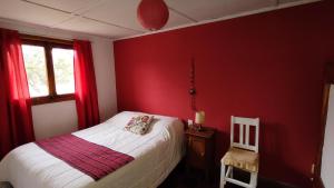 a bedroom with red walls and a bed and a chair at El viejo boliche in Trevelin