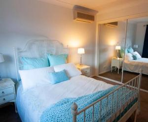 1 dormitorio con cama blanca y almohadas azules en Neogaia Bed & Breakfast, en Beecroft