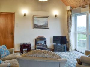 ein Wohnzimmer mit einem Sofa und einem TV in der Unterkunft The Cottage Gallt Y Balch in Bodorgan