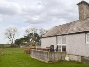 ein Haus mit einem Tisch und Stühlen außerhalb davon in der Unterkunft The Cottage Gallt Y Balch in Bodorgan