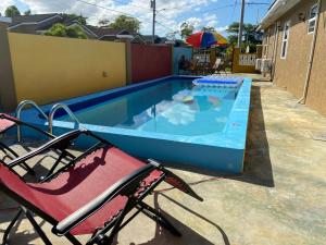 a swimming pool with two chairs and an umbrella at PARADISE VILLa 2 PRIVATE POOL in Ocho Rios