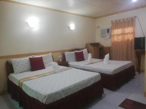 a hotel room with two beds and a tv at Lucky Garden Inn in Puerto Princesa City