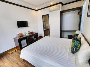 a bedroom with a large white bed and a tv at Vincent's House in Hoi An