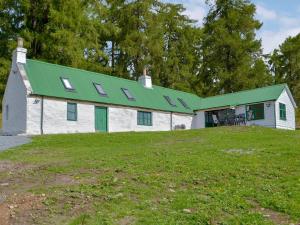 Casa blanca con techo verde y patio en Wester Laggan Cottage en Skye of Curr