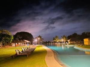 a row of chairs next to a swimming pool at night at Amaluna Resorts in Negombo