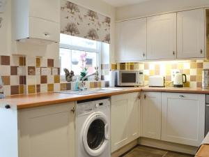 a kitchen with a washing machine and a microwave at The Costins in Allonby