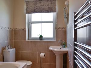 a bathroom with a toilet and a sink and a window at The Costins in Allonby