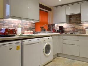 a kitchen with white cabinets and a washer and dryer at Church Barn in North Petherwin