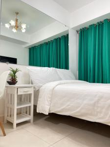 um quarto com uma cama branca e cortinas verdes em Kyoto apartment em Manila
