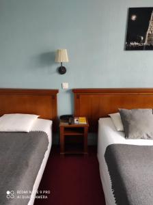 une chambre d'hôtel avec deux lits et une table avec une lampe dans l'établissement Hôtel Verlaine, à Paris