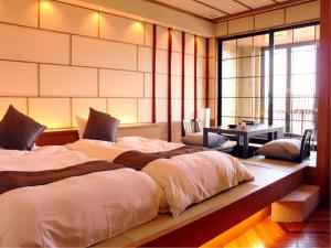 a bedroom with a large bed with a desk and windows at Resort Hills Toyohama Soranokaze in Toba