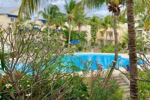 a swimming pool with palm trees in front of a hotel at Maison à proximité de la plage - LE TAMIER - Flic en Flac in Flic-en-Flac