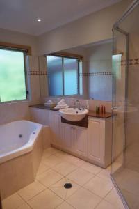 a bathroom with a tub and a sink and a shower at REDGUM RETREAT BRIGHT - Luxury Spa Villa in Bright