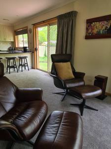 a living room with leather furniture and a kitchen at REDGUM RETREAT BRIGHT - Luxury Spa Villa in Bright