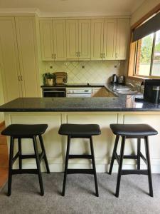 a kitchen with two bar stools and a counter at REDGUM RETREAT BRIGHT - Luxury Spa Villa in Bright