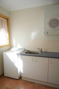 a kitchen with white cabinets and a sink and a window at REDGUM RETREAT BRIGHT - Luxury Spa Villa in Bright