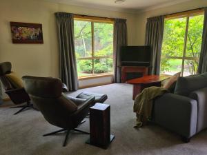 a living room with a couch and chairs and a television at REDGUM RETREAT BRIGHT - Luxury Spa Villa in Bright