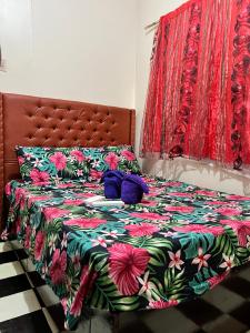 a bed with a floral bedspread and purple pillows on it at May’s Homestay in Cebu City