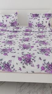 a white bed with purple flowers on it at PURE WELLNESS SEA-VIEW Beluga & Dolphin Luxury HOTEL apartments in Batumi
