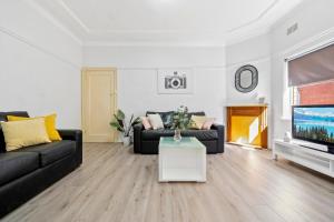 a living room with two black couches and a tv at Burwood Newly Renovated 2 Bedroom Apartment in Sydney