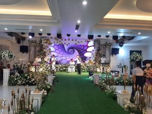a banquet hall with a green carpeted aisle with flowers at Nhà hàng - Khách sạn Sơn Nữ in Bak Kan