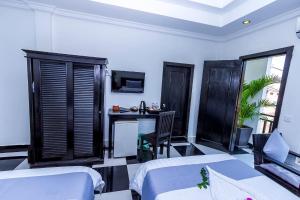 a room with two beds and a desk and a tv at Rithy Rine Angkor Residence in Siem Reap