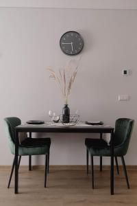 a dining room table with chairs and a clock on the wall at Cosy 1 bedroom apartment in the heart of old town with parking in Kaunas