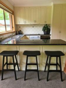 a kitchen with two bar stools and a counter at DELANY VILLAS BRIGHT - Spa luxury on Delany Avenue in Bright
