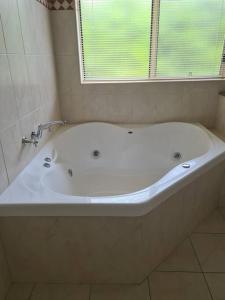 a white bath tub in a bathroom with a window at DELANY VILLAS BRIGHT - Spa luxury on Delany Avenue in Bright