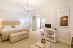 a bedroom with a bed and a couch and a television at Harbour House Hotel - Adventure Pads in Hermanus
