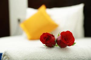 two red roses sitting on a white towel on a bed at SpiceGreen Homestay,Thekkady in Thekkady