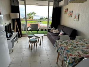 ein Wohnzimmer mit einem Sofa und einem Tisch in der Unterkunft Vue mer et sur la baie de Cannes piscine 450m2 randonnée VTT au pied de l Esterel in Théoule-sur-Mer