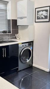 a kitchen with a washing machine and a sink at Cheerful 3 bedroom Townhouse with free parking. in Billericay