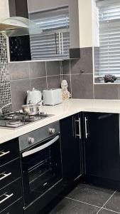 a kitchen with black cabinets and a stove top oven at Cheerful 3 bedroom Townhouse with free parking. in Billericay