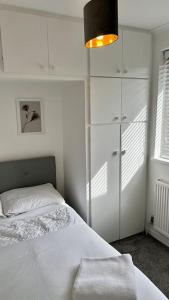 a white bedroom with a bed and a closet at Cheerful 3 bedroom Townhouse with free parking. in Billericay