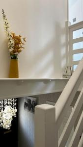 a white staircase with a vase with flowers in it at Cheerful 3 bedroom Townhouse with free parking. in Billericay