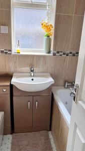 baño pequeño con lavabo y ventana en Cheerful 3 bedroom Townhouse with free parking. en Billericay