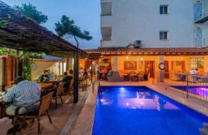 a pool at a hotel with people sitting at a restaurant at El Cortijo Escana in Es Cana