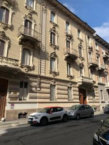 two cars parked in front of a large building at Il Sogno nel Cassetto in Turin