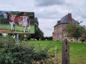 uma imagem de uma vaca num cartaz num campo em Chambre chez l'habitant 3 em Biville-la-Baignarde