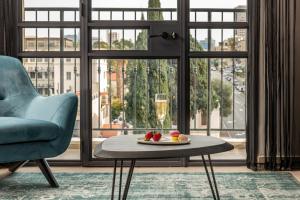 Hotel Botanica- Limited Edition By Fattal في حيفا: غرفة معيشة مع كرسي وطاولة مع كأس من النبيذ